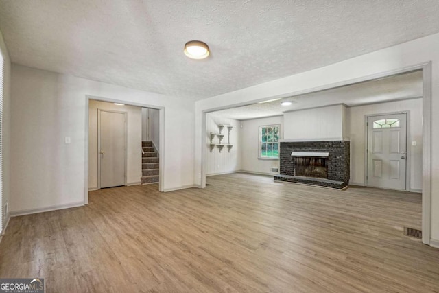 unfurnished living room featuring a textured ceiling, a fireplace, and light wood-type flooring