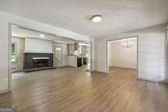 unfurnished living room featuring light hardwood / wood-style floors, a notable chandelier, and a textured ceiling