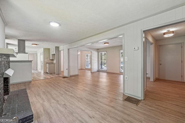 unfurnished living room featuring light hardwood / wood-style floors, a textured ceiling, and a fireplace