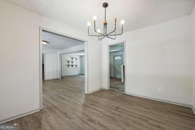 unfurnished dining area featuring a textured ceiling and hardwood / wood-style flooring