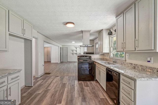 kitchen with black appliances, sink, wood-type flooring, island exhaust hood, and light stone counters