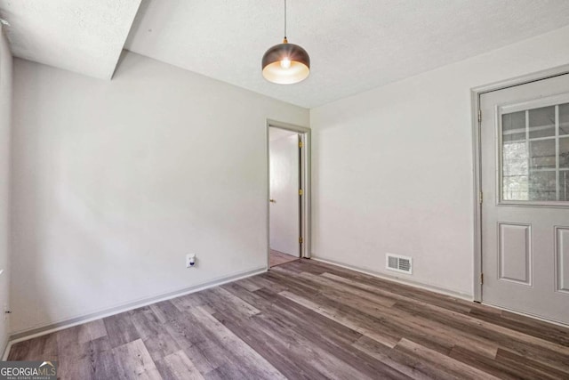 unfurnished room with a textured ceiling and wood-type flooring