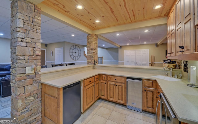 kitchen with kitchen peninsula, wine cooler, stainless steel fridge, decorative columns, and sink