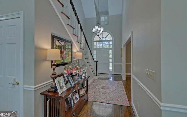 entryway with a towering ceiling, an inviting chandelier, and dark hardwood / wood-style floors