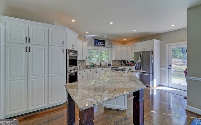 kitchen with decorative backsplash, a kitchen island, appliances with stainless steel finishes, a breakfast bar, and white cabinetry