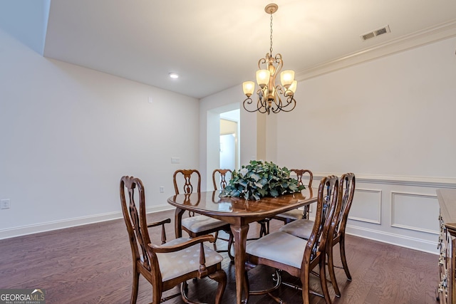 dining room with crown molding, dark wood-type flooring, and a chandelier