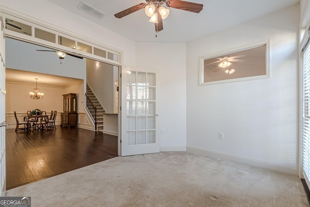 carpeted empty room featuring ceiling fan with notable chandelier