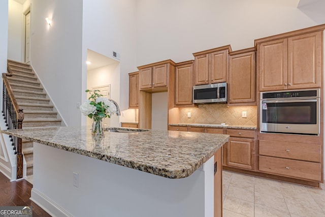 kitchen with sink, stone countertops, a kitchen breakfast bar, stainless steel appliances, and decorative backsplash