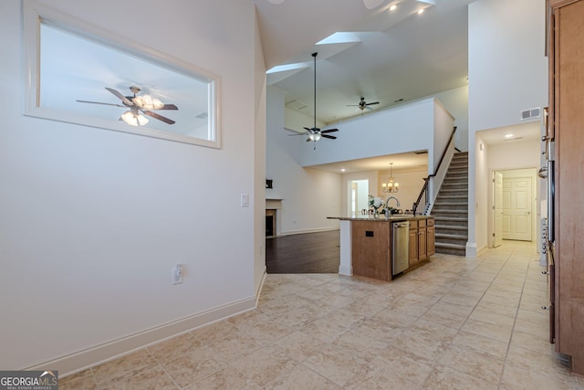 kitchen with sink, dishwasher, a towering ceiling, ceiling fan with notable chandelier, and decorative light fixtures