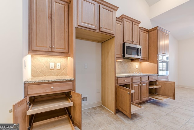 kitchen featuring light stone countertops, decorative backsplash, and stainless steel appliances