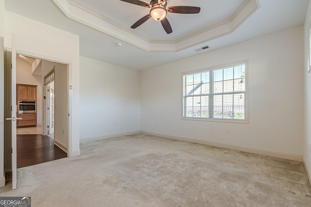 carpeted empty room with crown molding, ceiling fan, and a tray ceiling