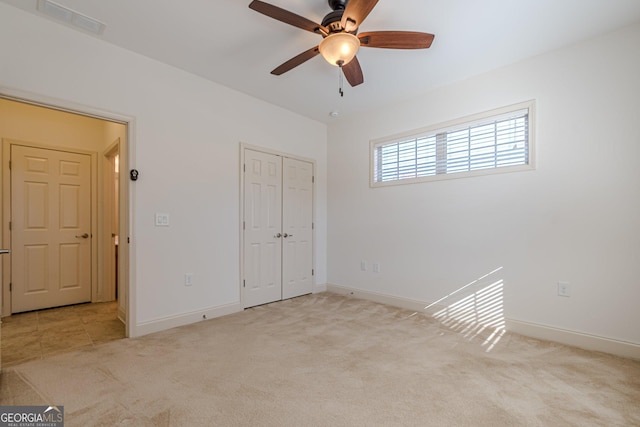 unfurnished bedroom with ceiling fan, a closet, and light carpet