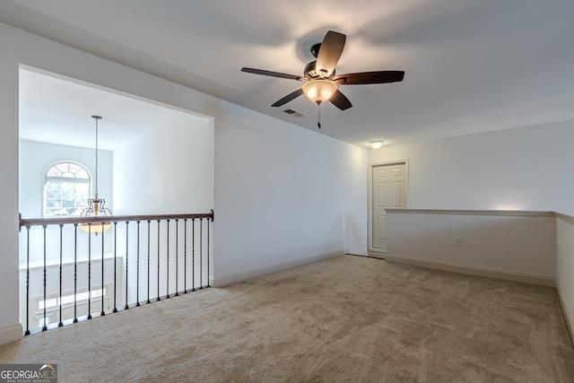 carpeted spare room with ceiling fan with notable chandelier