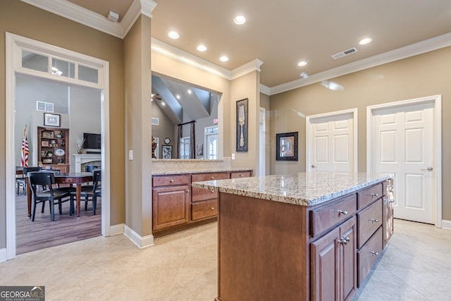 kitchen with light stone counters, crown molding, light tile patterned flooring, and a kitchen island