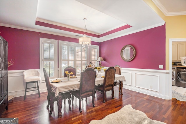 dining room featuring ornamental molding, dark wood-type flooring, a raised ceiling, and washing machine and dryer