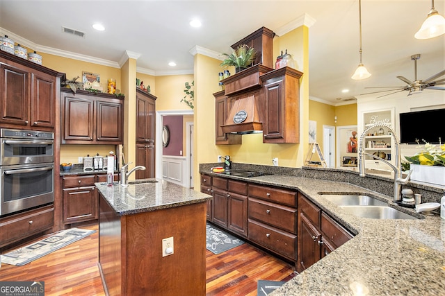 kitchen with pendant lighting, dark hardwood / wood-style flooring, sink, and dark stone countertops