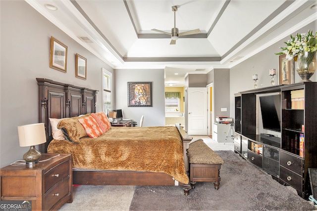 carpeted bedroom featuring ceiling fan, ensuite bath, a tray ceiling, and ornamental molding