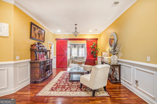 sitting room with a barn door, dark wood-type flooring, and crown molding