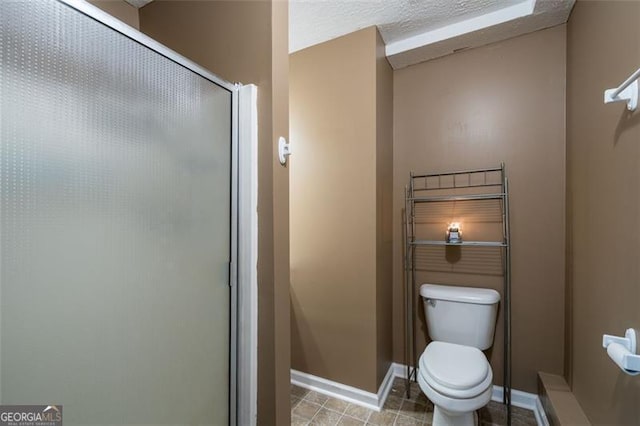 bathroom with a textured ceiling, toilet, and an enclosed shower