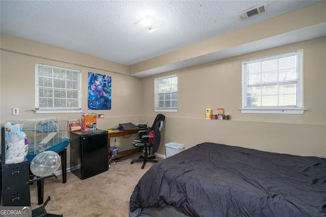 bedroom with a textured ceiling and light colored carpet