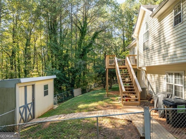 view of yard featuring a wooden deck, an outdoor structure, a fenced backyard, stairs, and a storage unit