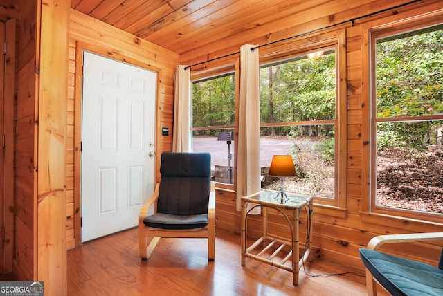 sitting room featuring wooden walls, light hardwood / wood-style floors, a healthy amount of sunlight, and wooden ceiling