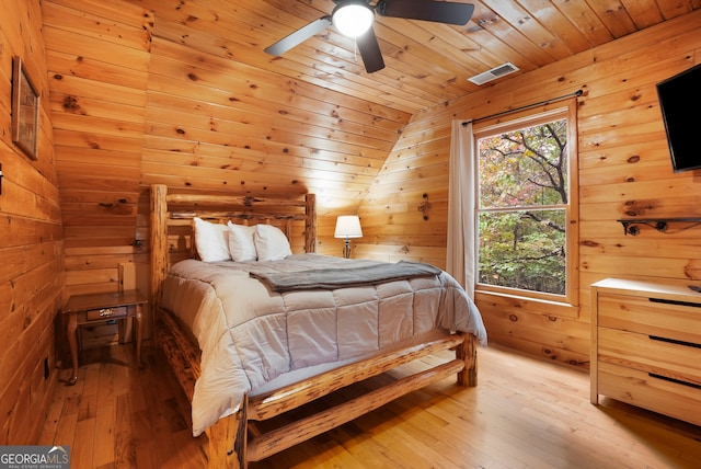 bedroom with light hardwood / wood-style floors, wood ceiling, wooden walls, and ceiling fan