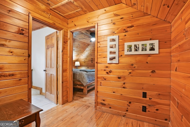 hall featuring lofted ceiling, wooden walls, wood ceiling, and light hardwood / wood-style floors