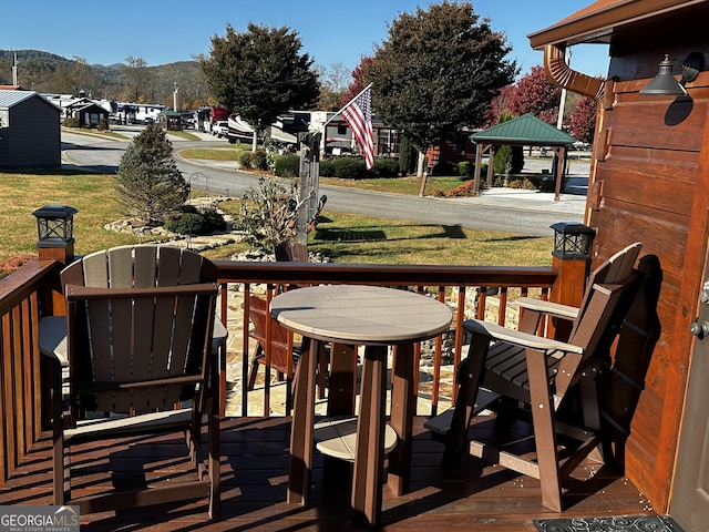 wooden terrace featuring a gazebo, a mountain view, and a lawn