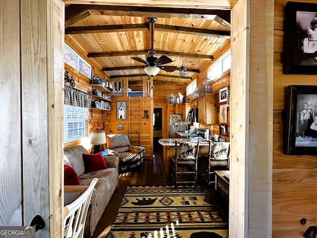 living room featuring vaulted ceiling with beams, a healthy amount of sunlight, wood-type flooring, and wooden walls