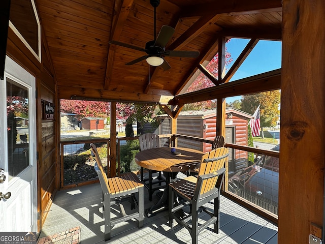 sunroom / solarium featuring lofted ceiling with beams, wooden ceiling, and ceiling fan