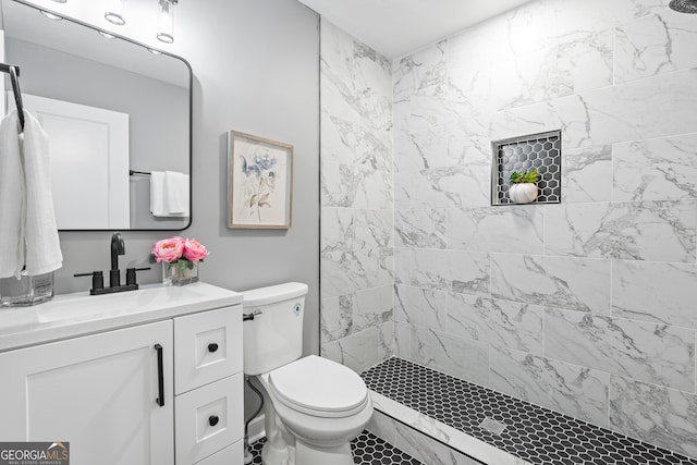 bathroom with vanity, toilet, and a tile shower