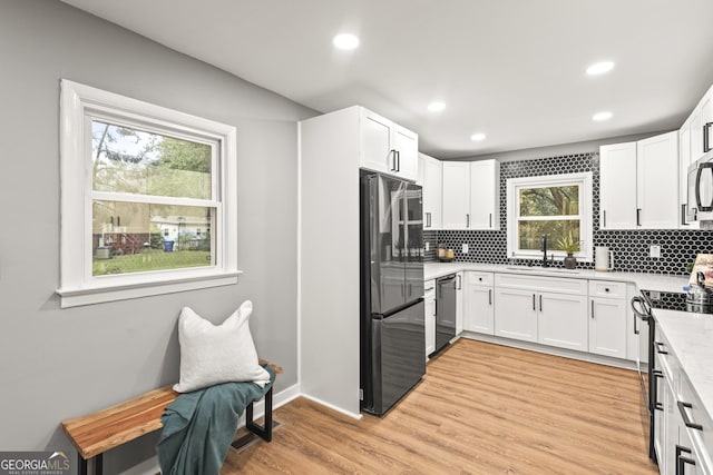 kitchen with white cabinetry, stainless steel appliances, sink, and light hardwood / wood-style flooring