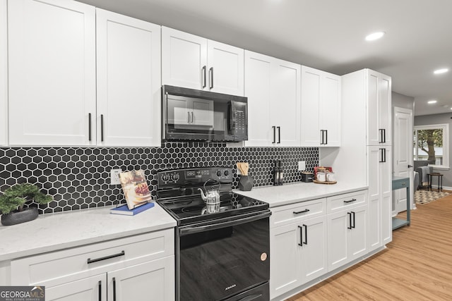 kitchen featuring white cabinetry, decorative backsplash, light hardwood / wood-style flooring, and black appliances