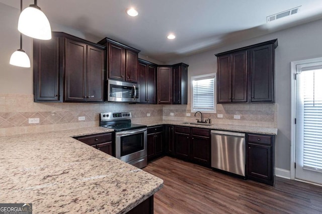 kitchen with decorative backsplash, dark wood-type flooring, hanging light fixtures, sink, and appliances with stainless steel finishes