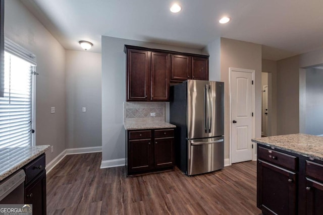 kitchen featuring dark wood-type flooring, light stone countertops, dark brown cabinetry, and stainless steel refrigerator