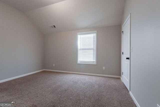 carpeted empty room with lofted ceiling