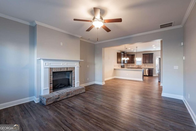 unfurnished living room with crown molding, a brick fireplace, dark hardwood / wood-style floors, and ceiling fan