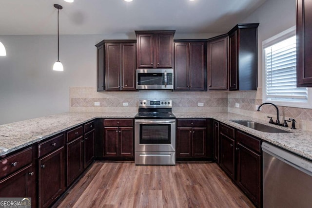 kitchen with hardwood / wood-style floors, hanging light fixtures, backsplash, appliances with stainless steel finishes, and sink