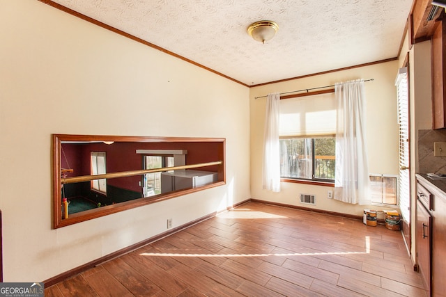 interior space featuring crown molding, light hardwood / wood-style floors, and a textured ceiling