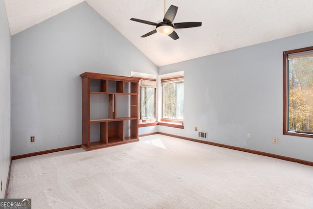 unfurnished room featuring plenty of natural light, ceiling fan, light colored carpet, and high vaulted ceiling