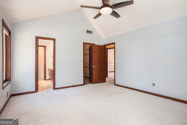 unfurnished bedroom with high vaulted ceiling, ensuite bathroom, ceiling fan, a spacious closet, and light colored carpet