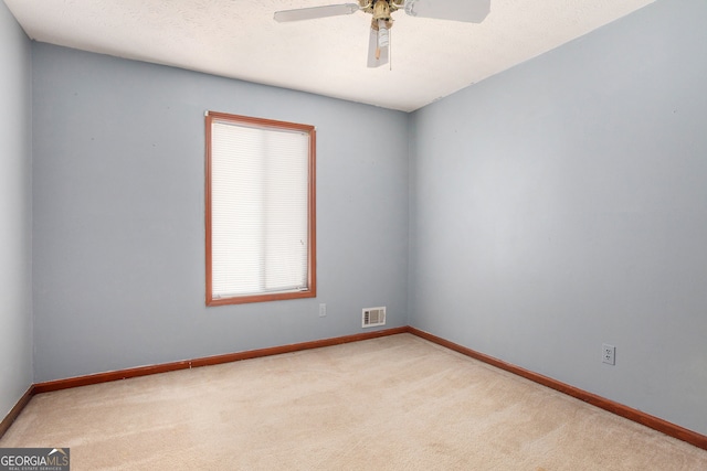 carpeted empty room featuring ceiling fan and a textured ceiling