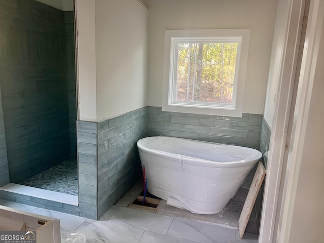 bathroom featuring a wainscoted wall, a freestanding bath, tile walls, and tiled shower