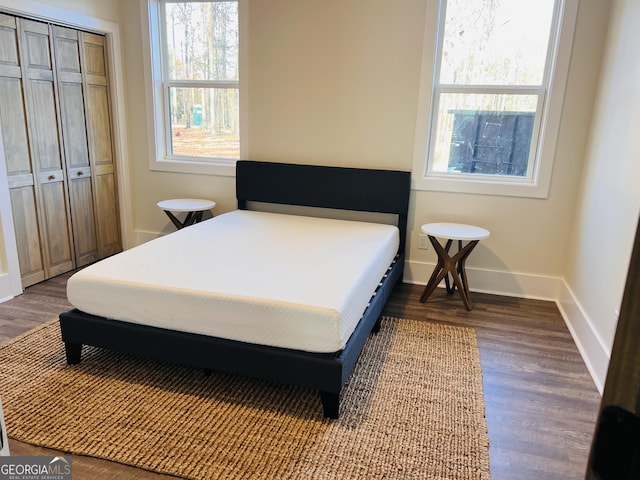 bedroom with a closet, baseboards, and dark wood-style flooring