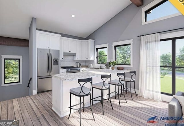 kitchen with a breakfast bar area, a peninsula, a sink, white cabinets, and appliances with stainless steel finishes