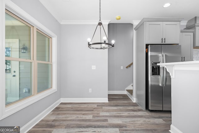 dining space with crown molding, a chandelier, and hardwood / wood-style flooring