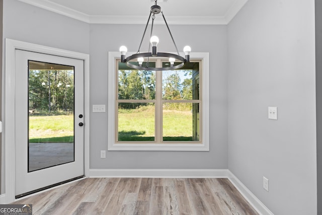 unfurnished dining area with light wood-type flooring, a chandelier, and crown molding