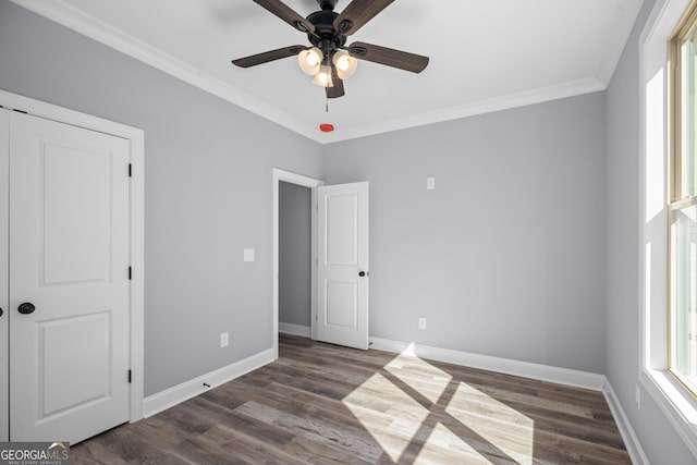 unfurnished bedroom featuring ceiling fan, a closet, dark hardwood / wood-style floors, and crown molding