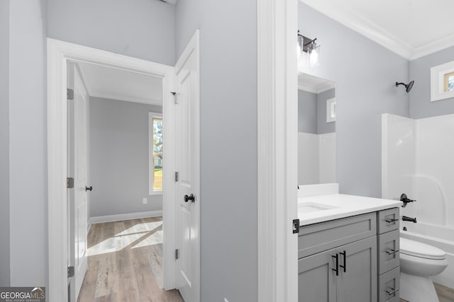 full bathroom featuring toilet, hardwood / wood-style floors, shower / bathing tub combination, ornamental molding, and vanity